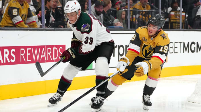 Coyotes defenseman Travis Dermott and Golden Knights center Brendan Brisson fight for a puck in a game.